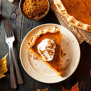 pumpkin pie with slice of pie topped with whipped cream