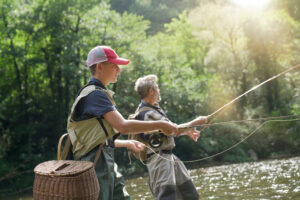 A father and his son fly fishing in summer on a beautiful trout