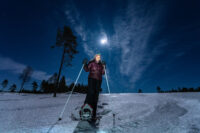 woman snowshoeing with full moon above