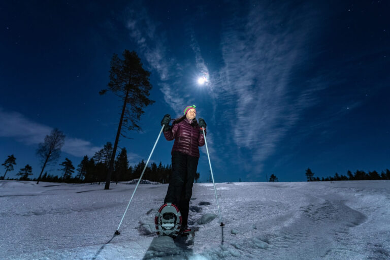 person snowshoeing with full moon up above